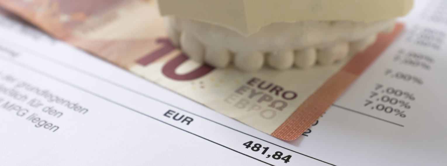 Ein Zahnmodell auf einem 10-Euro-Schein und eine Zahnarztrechnung
