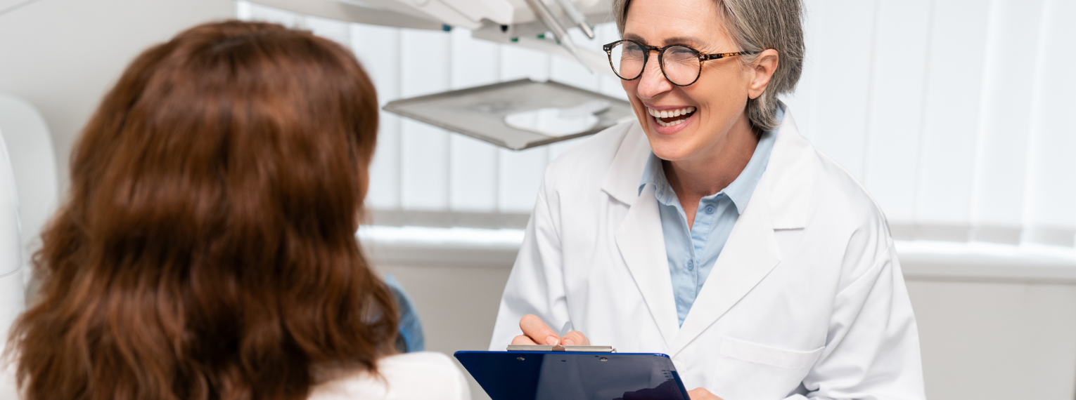 Eine Zahnärztin lächelt ihre Patientin an.