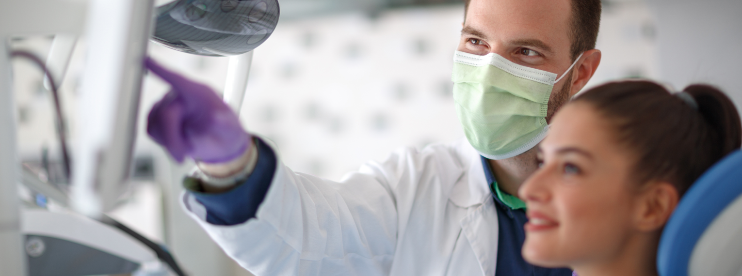 Eine Patientin, die lächelt, während ihr Zahnarzt ihr etwas erklärt.