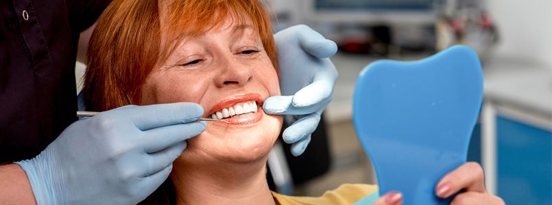 Zu sehen ist eine Frau, die von ihrem Zahnarzt dazu beraten wird, was eine komplette Zahnsanierung kosten wird.