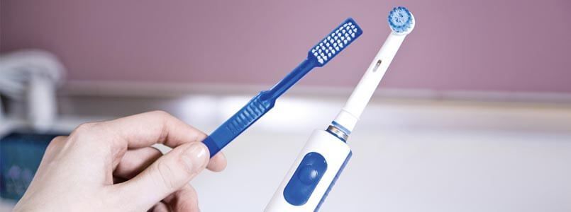 Ein Patient überlegt, ob eine elektrische Zahnbürste besser ist als eine Handzahnbürste oder ob dies nur ein Zahnmythos ist.