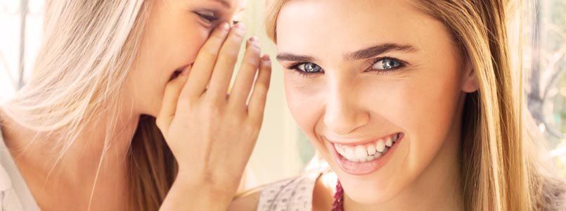 Zwei Frauen unterhalten sich über Gründe für Zahnverfärbungen.