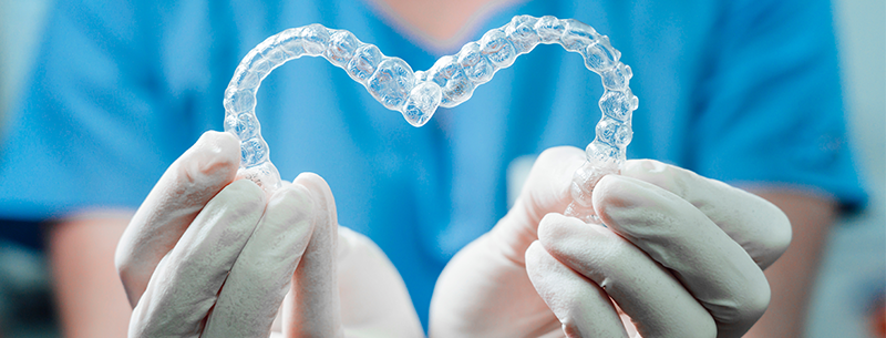 Zu sehen sind zwei Invisalign Zahnspangen, die ein Herz formen.