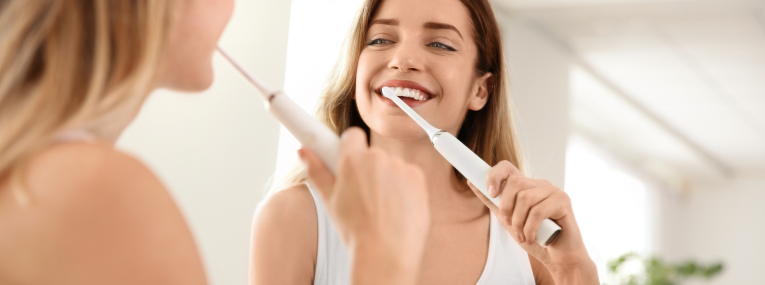 Eine Frau putzt sich die Zähne, um Plaque von ihren Zähnen zu entfernen.