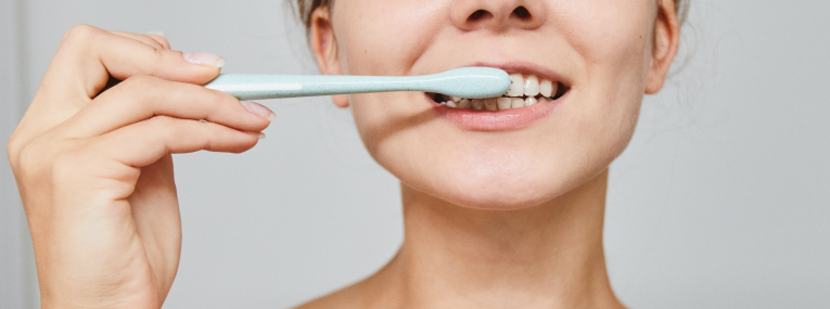 Eine Frau putzt sich die Zähne und stellt Zahnfleischbluten bei sich fest.