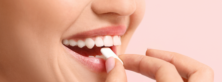 Zu sehen ist eine Person, die ein Zahnpflegekaugummi verwendet.