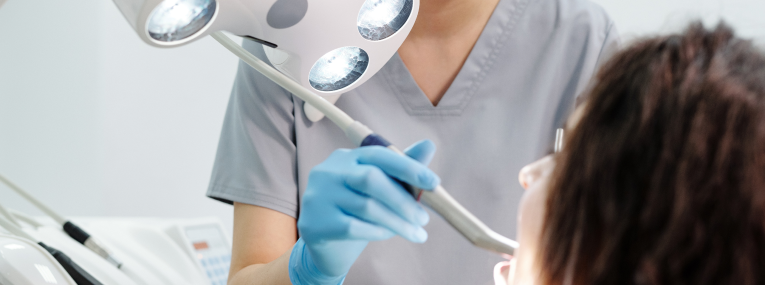 Zu sehen ist eine Patientin, der Zahnstein entfernt wird.