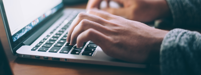 Ein Mann tippt am Laptop, um herauszufinden, wie er seine Zahnzusatzversicherung kündigen kann.