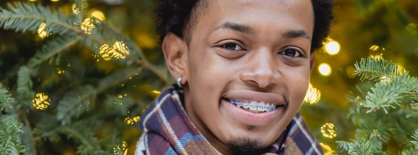 Zu sehen ist ein Jugendlicher mit einer Zahnspange.