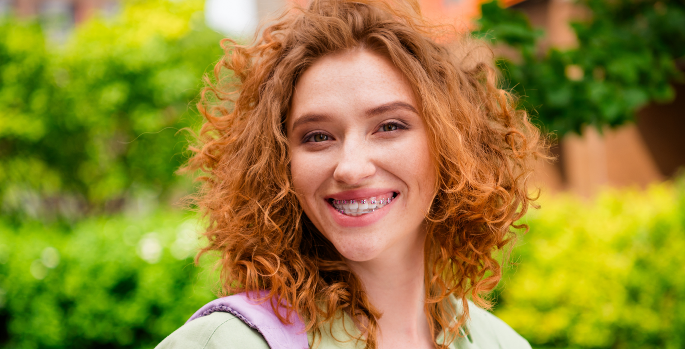 Eine junge Frau mit fester Zahnspange lächelt.