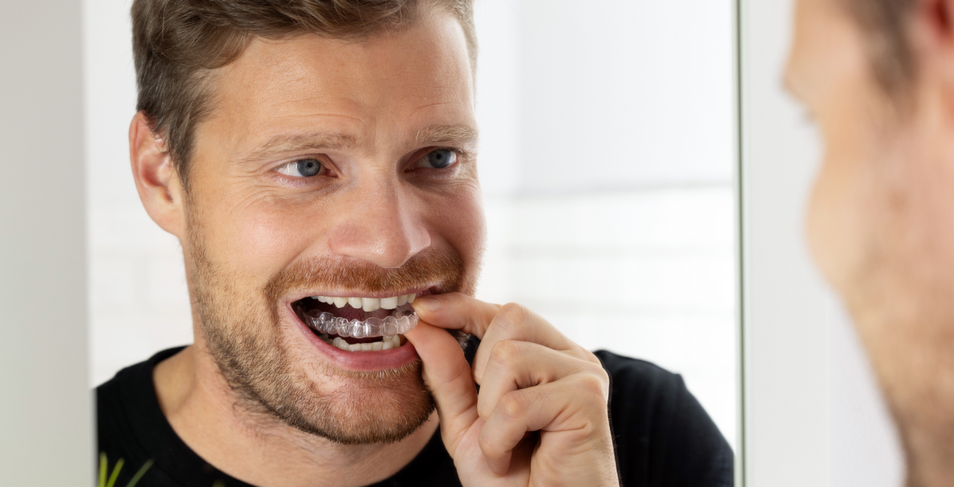 Ein Mann zieht seine Invisalign-Schiene an.