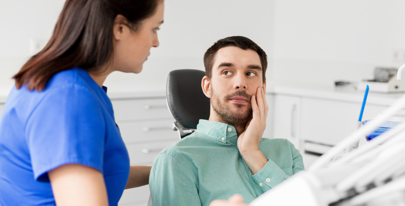 Ein Mann mit Zahnschmerzen wird von einer Zahnärztin behandelt.