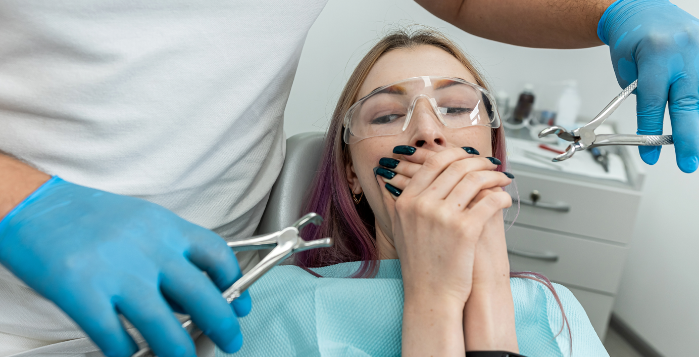 Eine verängstigte Patientin hält sich beim Zahnarzt den Mund zu.