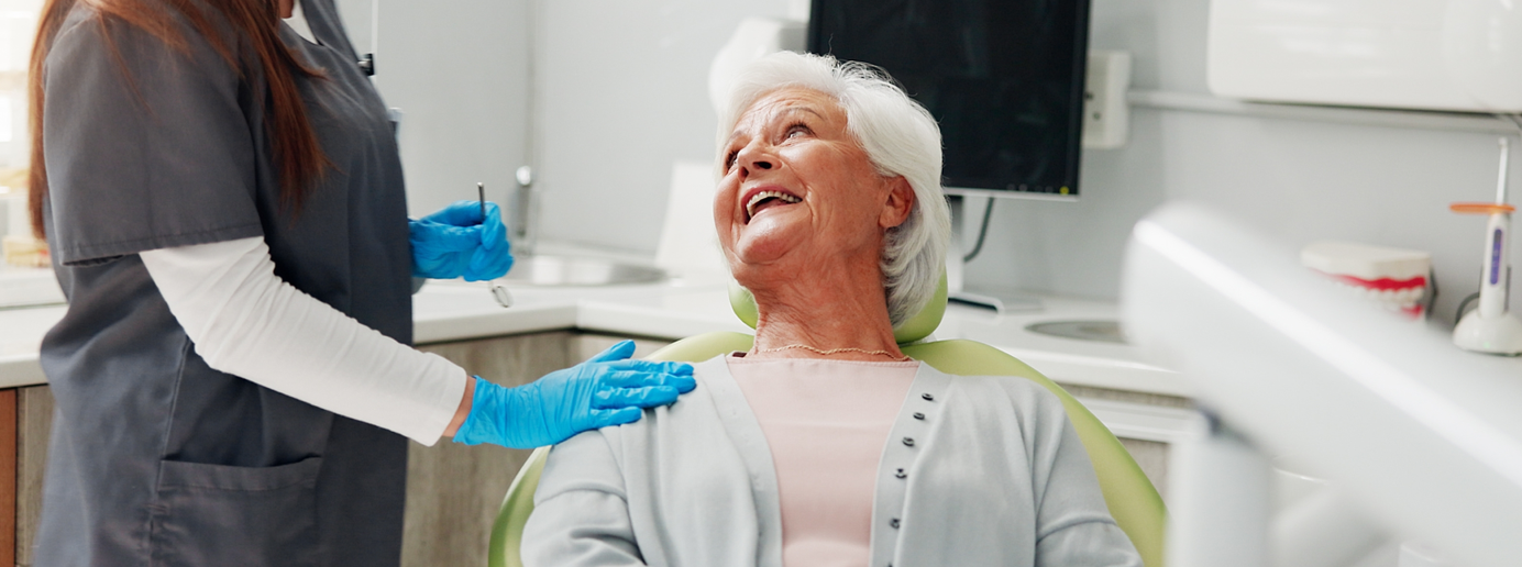 Eine Patientin, die ihren Zahnarzt bei ihrer Routineuntersuchung anlächelt.
