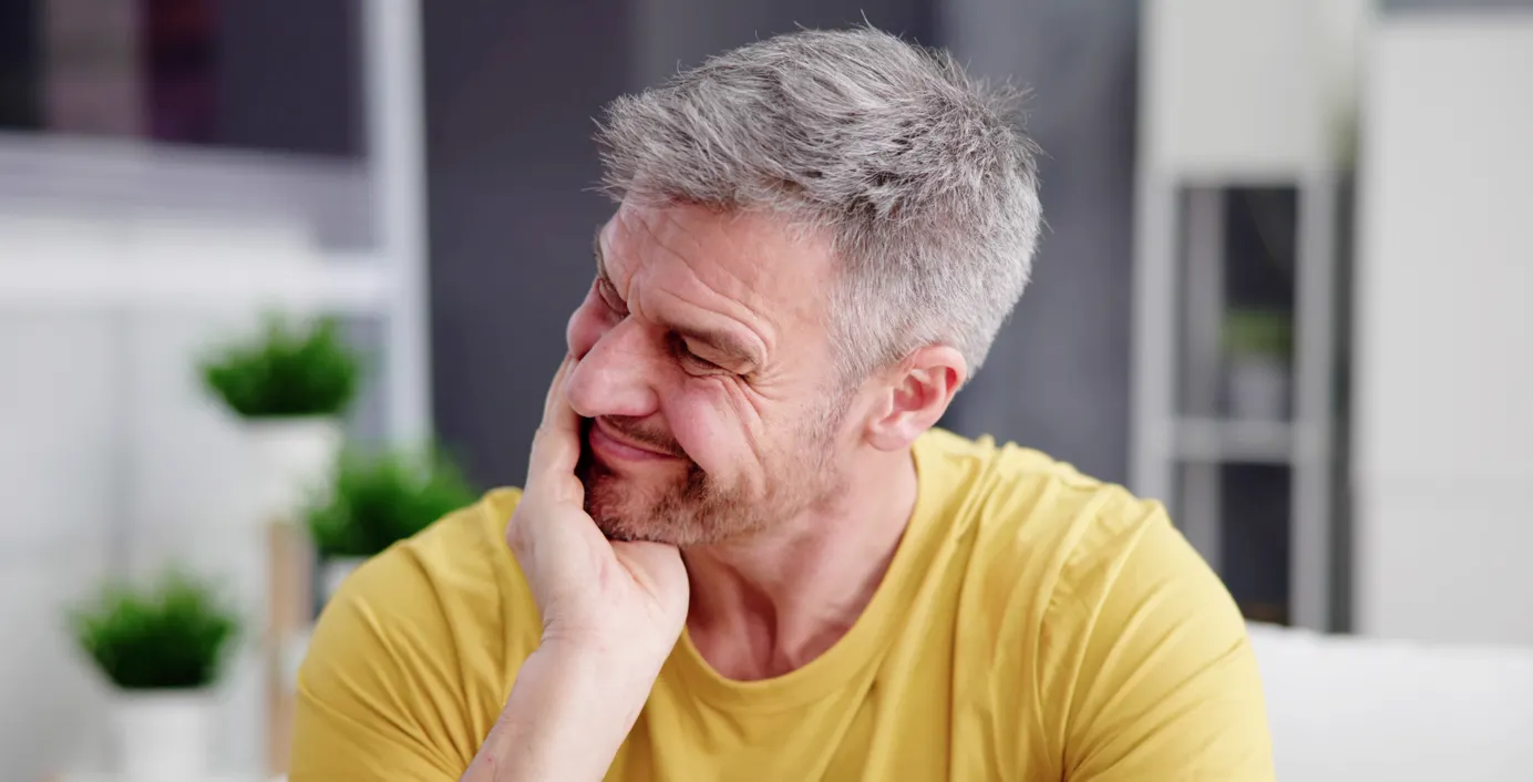 Ein Mann hat starke Kieferschmerzen wegen CMD.