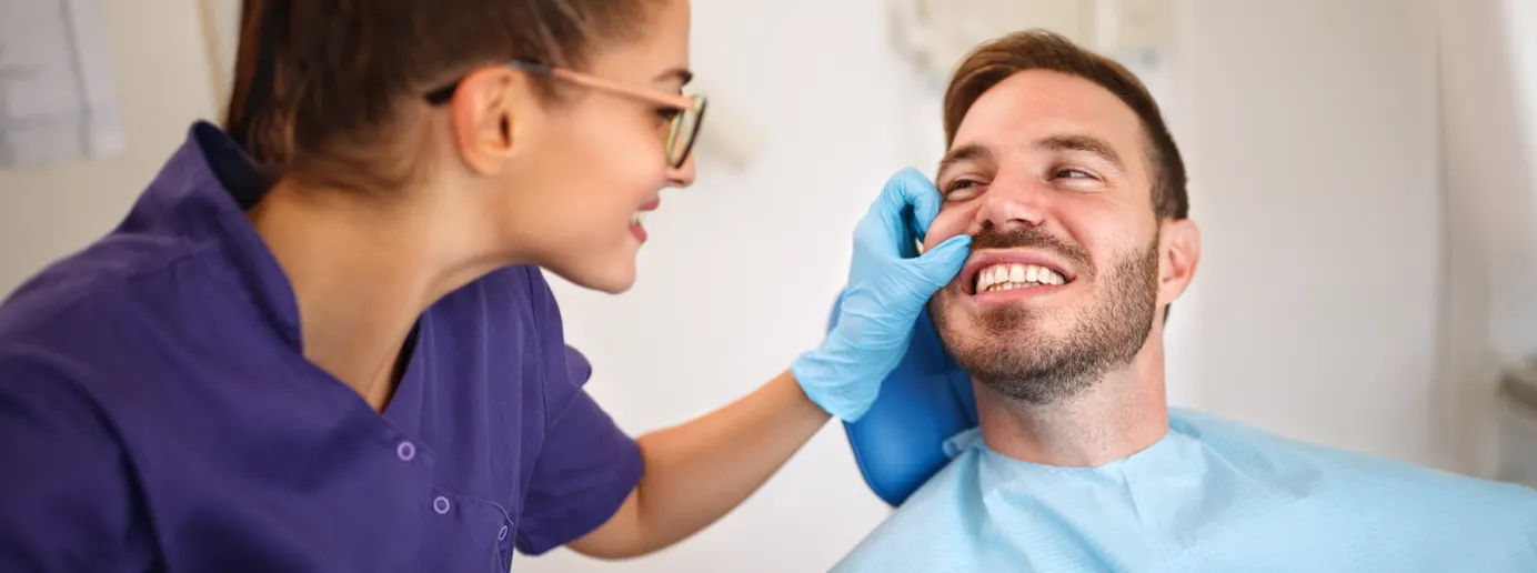 Eine Zahnärztin untersucht Zahnfleischtaschen eines Patienten.