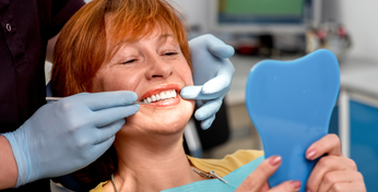 Eine Frau bekommt Ihre Zähne für eine Wurzelbehandlung vom Zahnarzt untersucht.