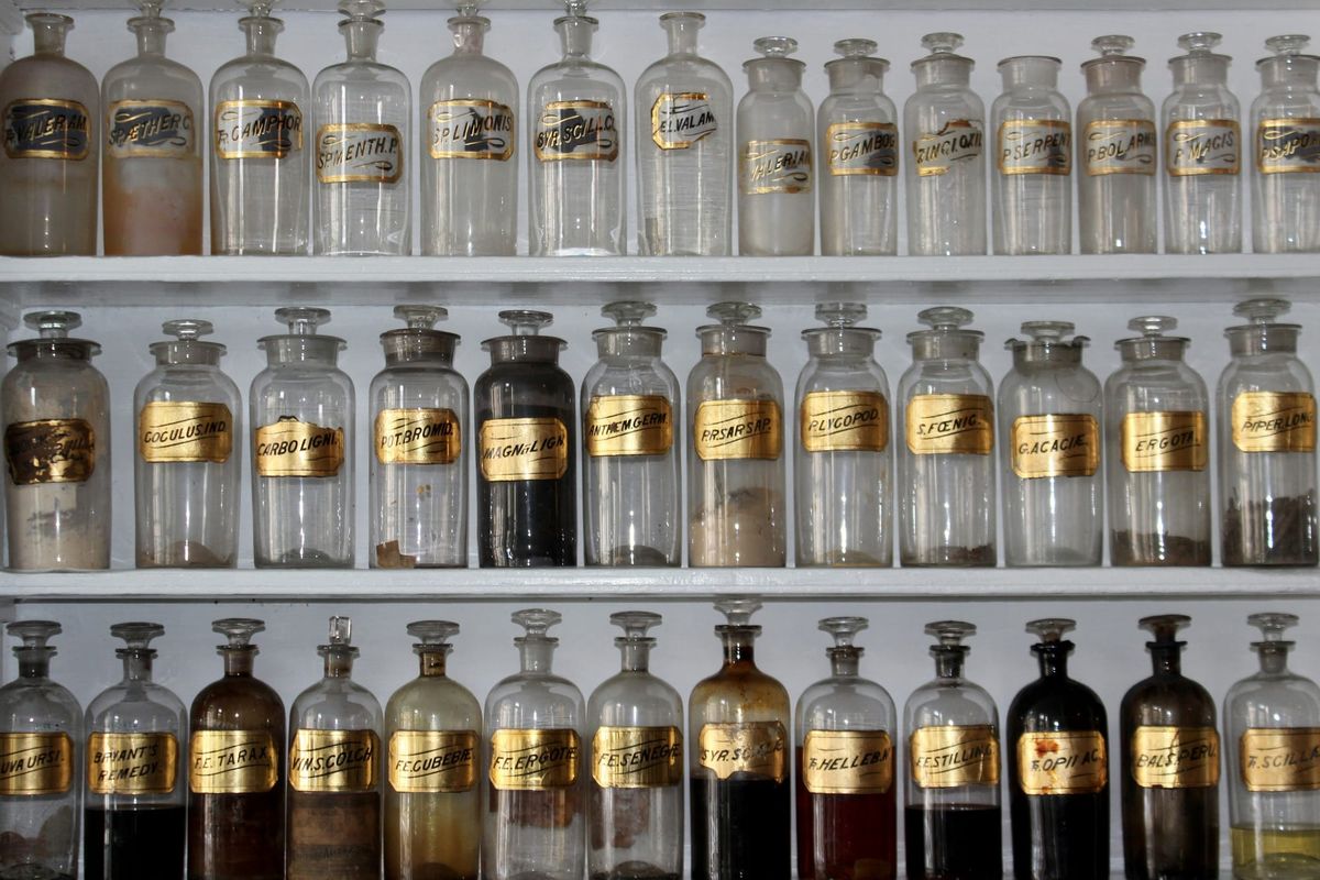 Photo of antique glass medicine or herb bottles with gold labels and stopper tops.