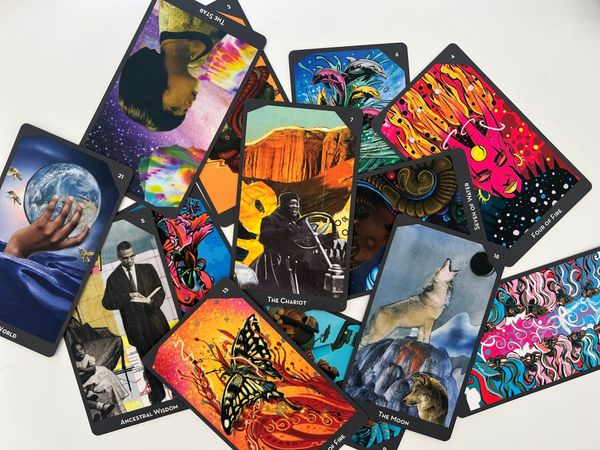Photo of tarot cards from The Lineages of Change Tarot deck. Some are bright reds and oranges, others are darkers blues and purples.
