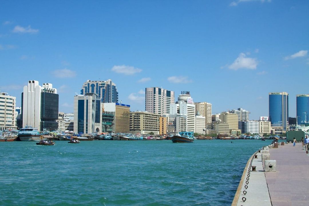 Abras y barcas navegan por el Dubai Creek frente a los edificios de oficinas de Deira en un día soleado.