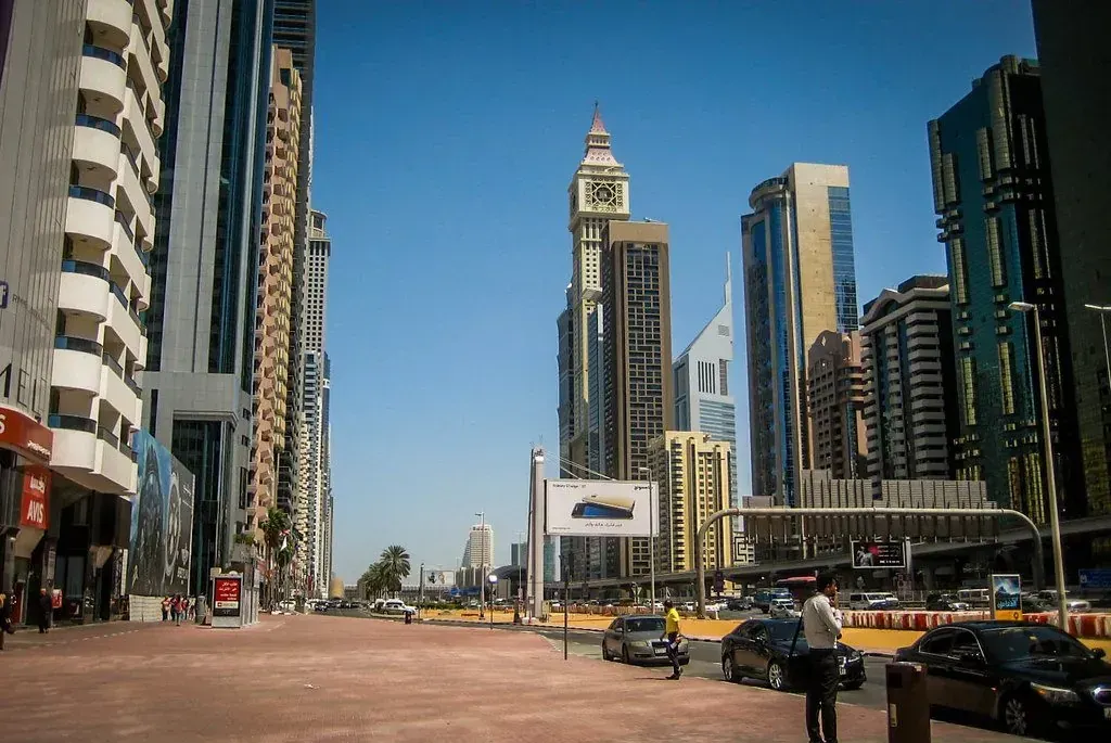 High-rise towers along a main road in Dubai under a clear sky.