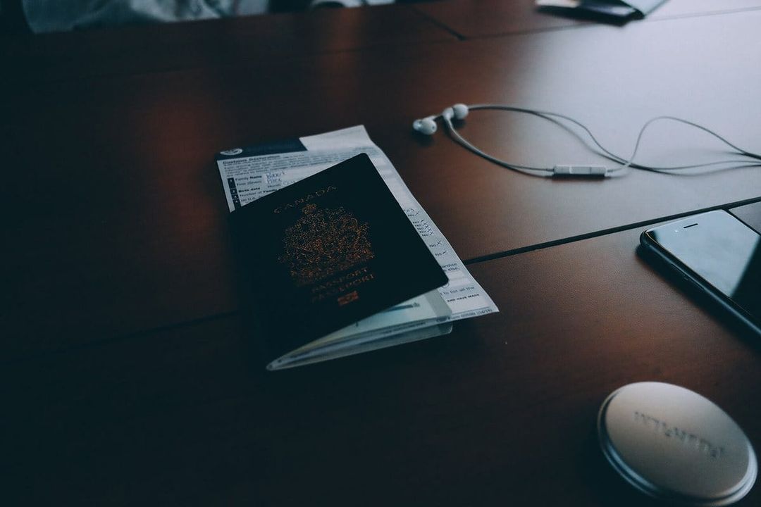 Passeport posé sur un formulaire de déclaration douanière, sur une table en bois, à côté d'écouteurs et d'un téléphone.