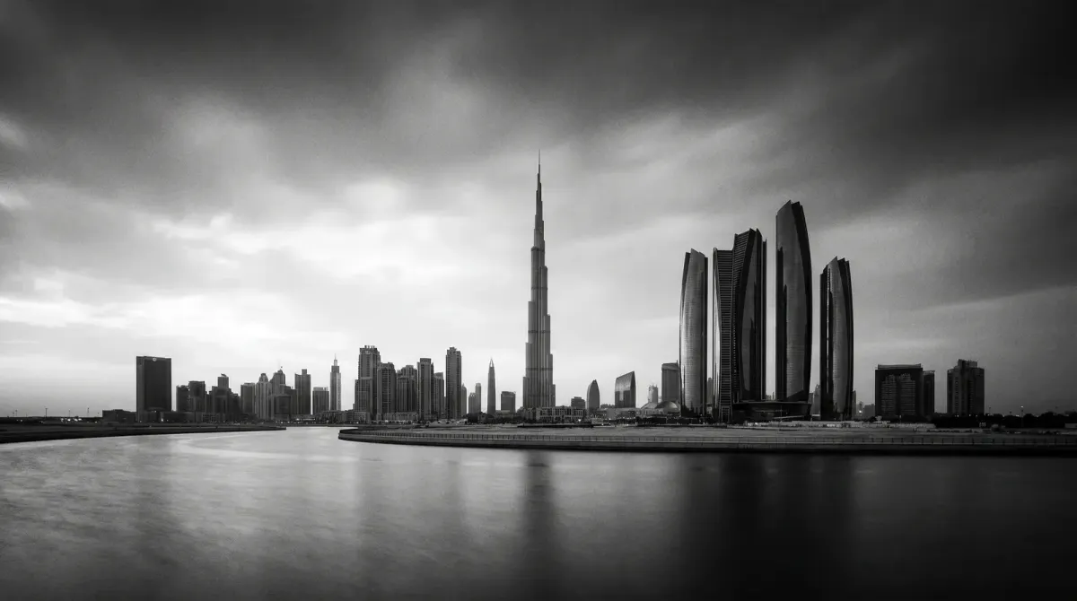 Black-and-white Dubai skyline with the Burj Khalifa and Downtown towers reflected in still water