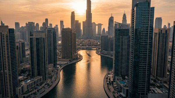 A wide aerial of Dubai Business Bay and the Burj Khalifa at golden hour, representing a US citizen setting up a Dubai company