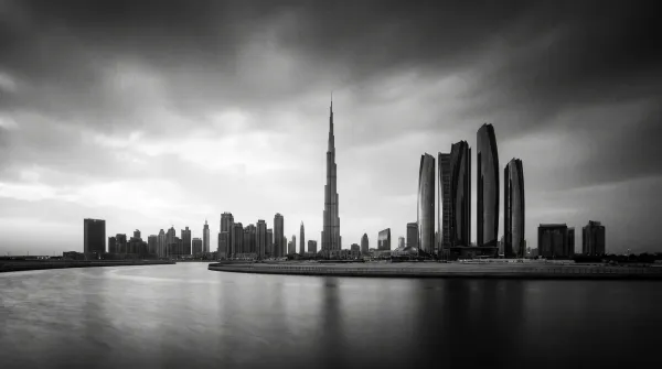 Black-and-white Dubai skyline with the Burj Khalifa and Downtown towers reflected in still water