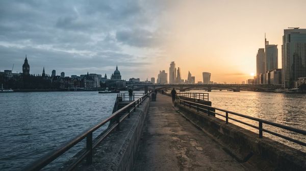 A Thames riverside path with the London skyline at dawn, cool light warming to gold, evoking a UK wealth-restructuring move