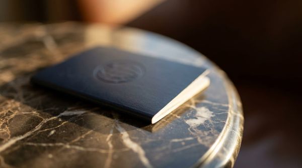 A dark premium passport resting on a marble surface in warm light, representing a second citizenship