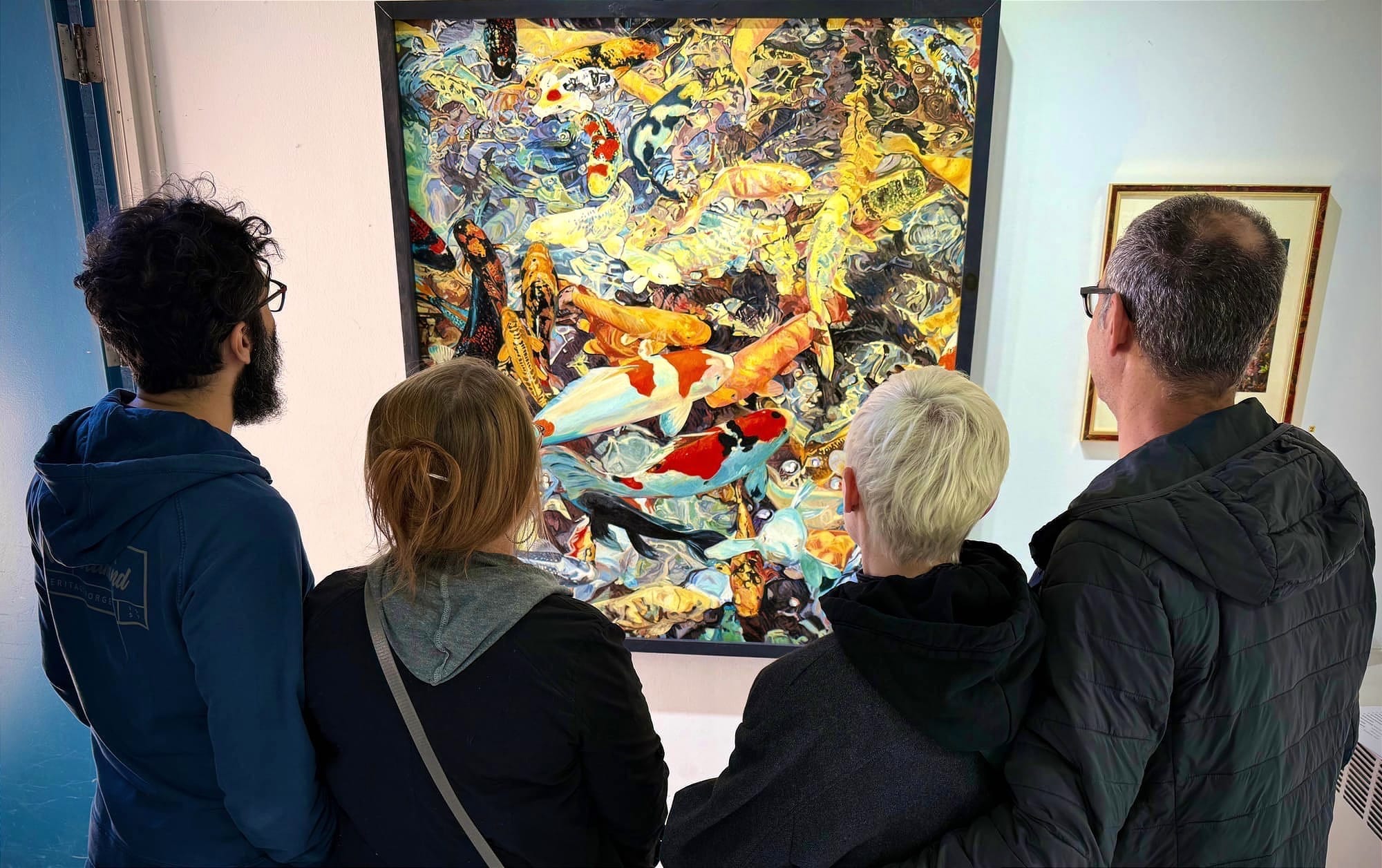 Seen from behind, four gallery visitors view a large, colourful painting hung on a white wall.