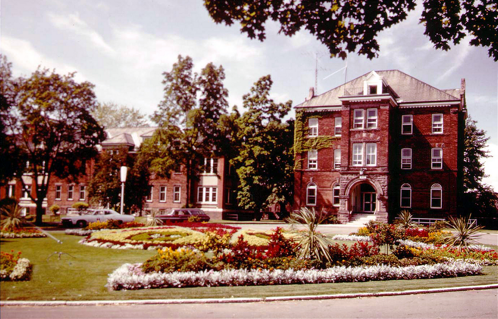 Archival photo of the Humber College Administration building, with a landscaped garden and trees in the foreground.