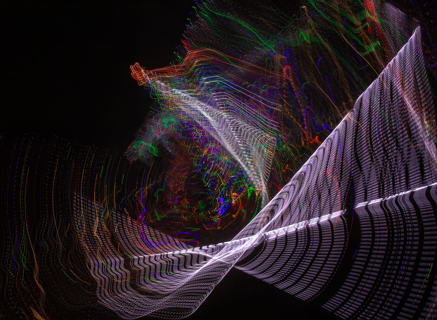 A windmill of multi-coloured light spirals outward from a black background.