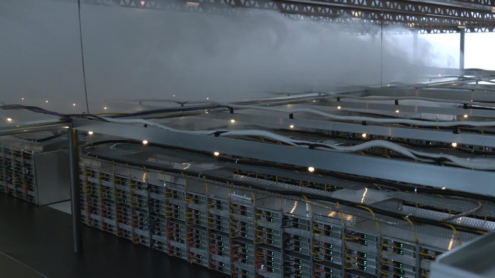 Wide shot of rows of servers  in a data centre, surrounded by clouds of steam.