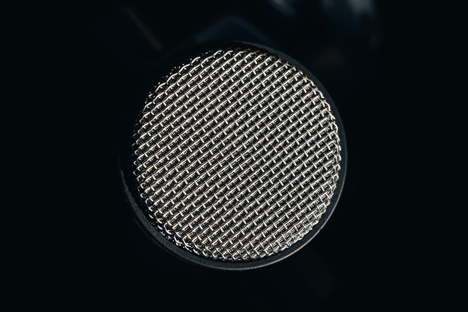 A silver microphone grille against a black background.