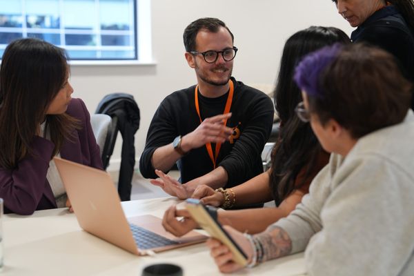 A trainer from ProMo Cymru talking to a group while sat around a desk. 