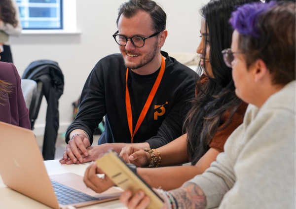 A member of the Newid team supporting someone on their laptop.