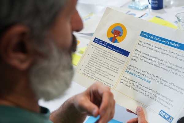 A man holding a piece of paper that shows a user persona for Newid.