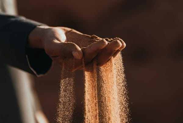 a person holding sand in their hands