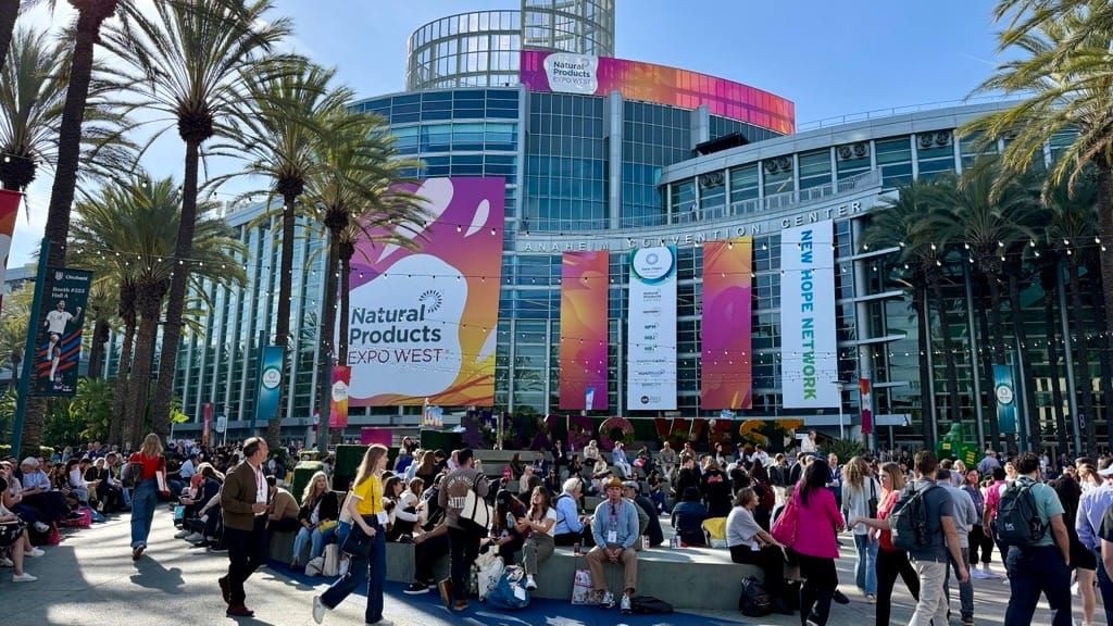 Busy convention hall with many attendees and exhibitor booths at Expo West.