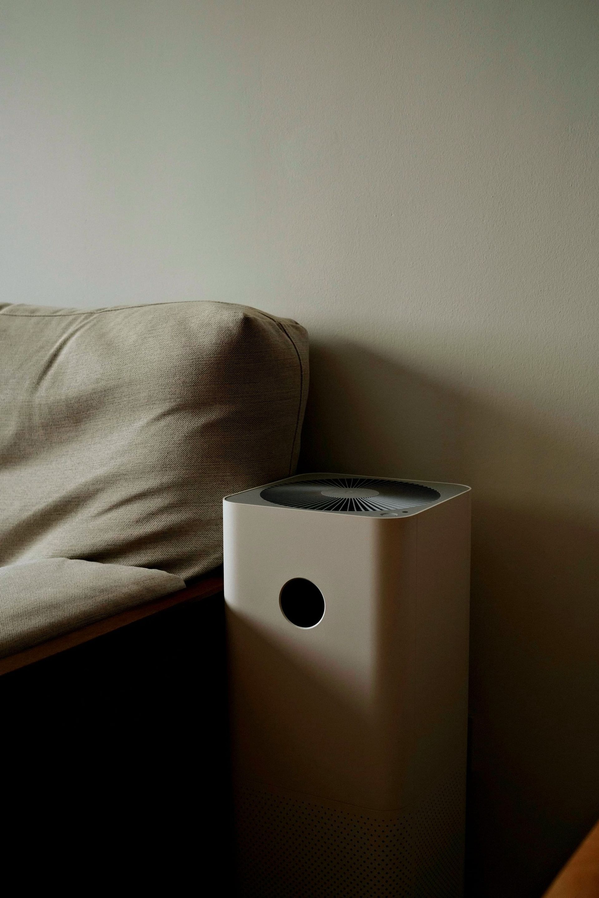 Compact air purifier in a black background showing vents and power button - choose an air purifier