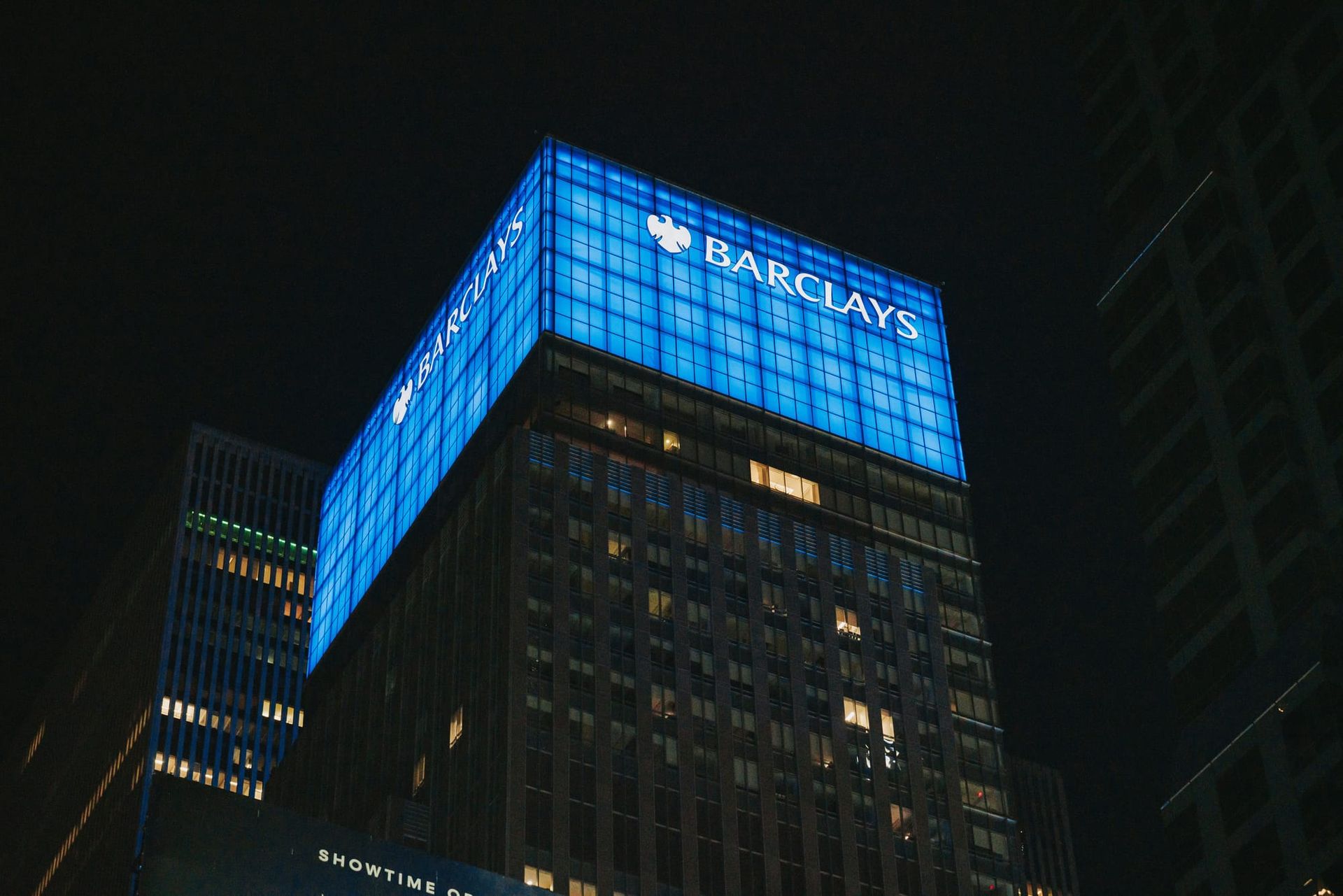 Illuminated high-rise building against the night sky in New York City - Barclays job cuts