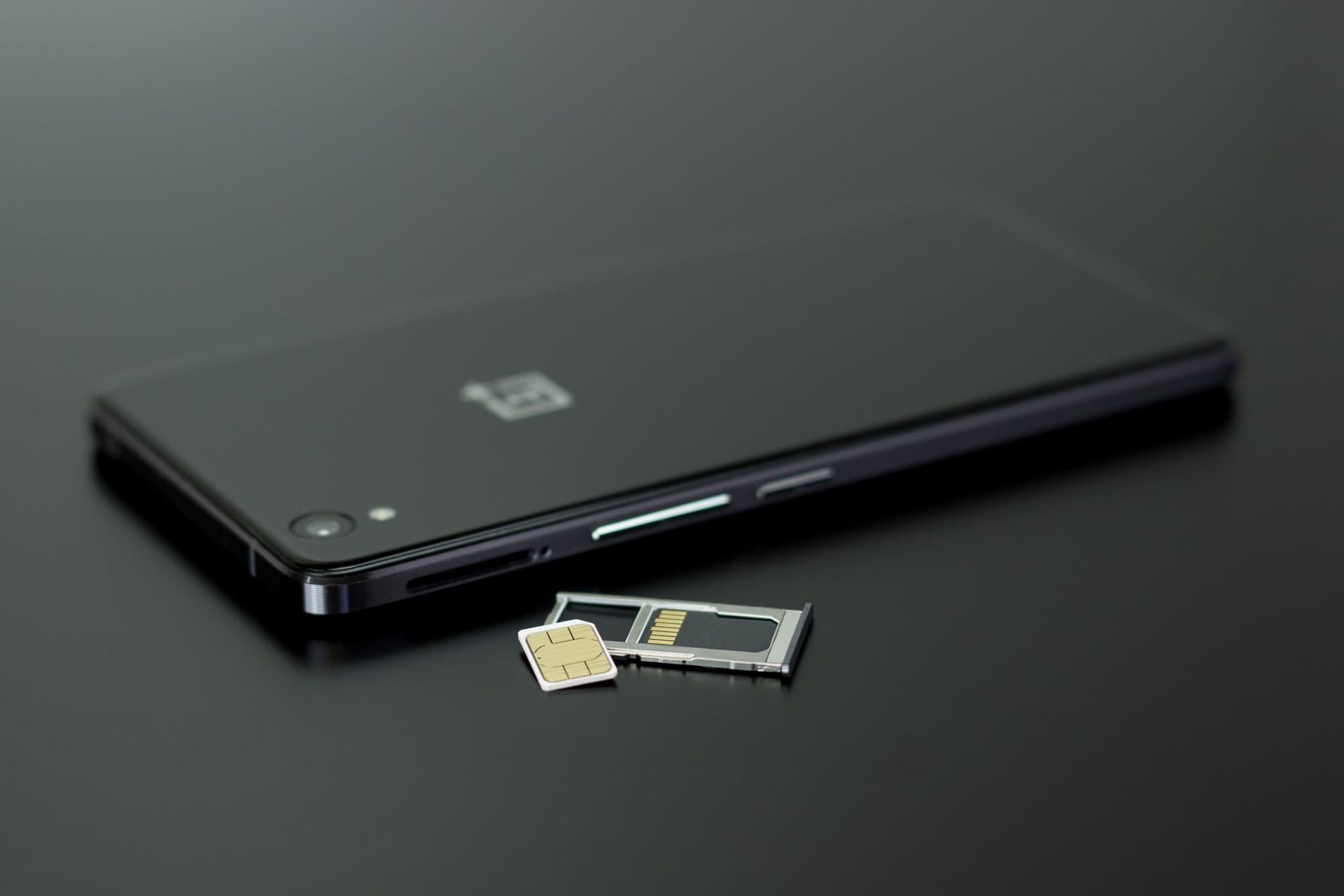 smartphone and SIM card arranged on a dark surface - mobile plan hidden fees