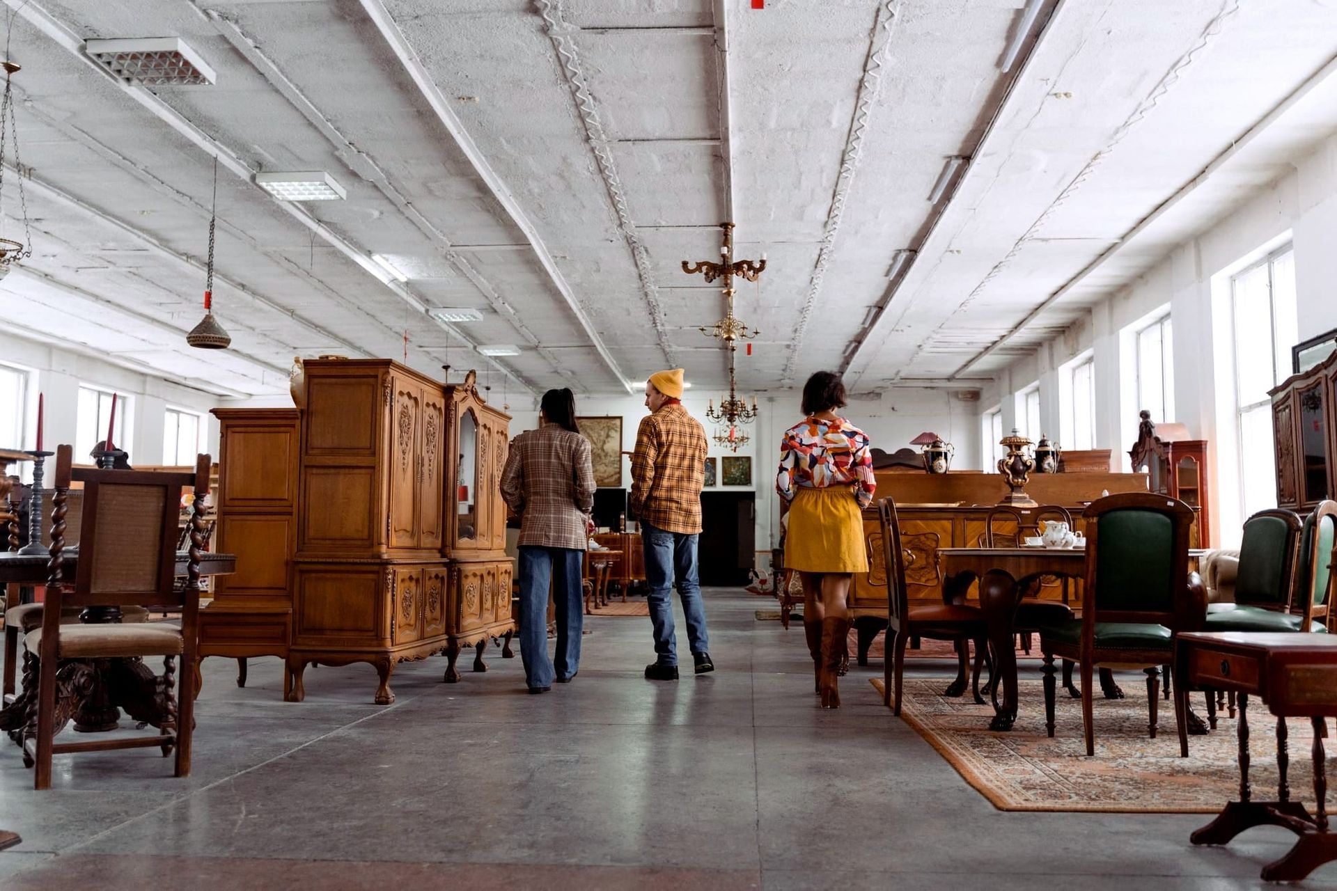 Three shoppers walking among wooden tables, cabinets and chairs inside a furniture store - October 2026 consumer sentiment