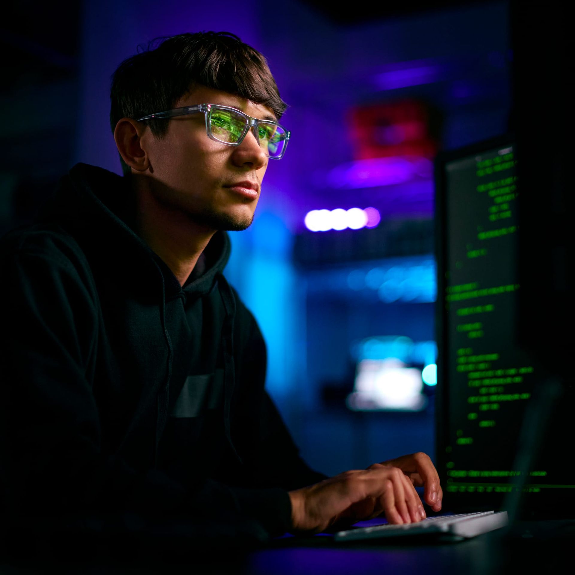 A person types programming code on a screen beside a keyboard and desktop monitor - Gemini 4 Carbon