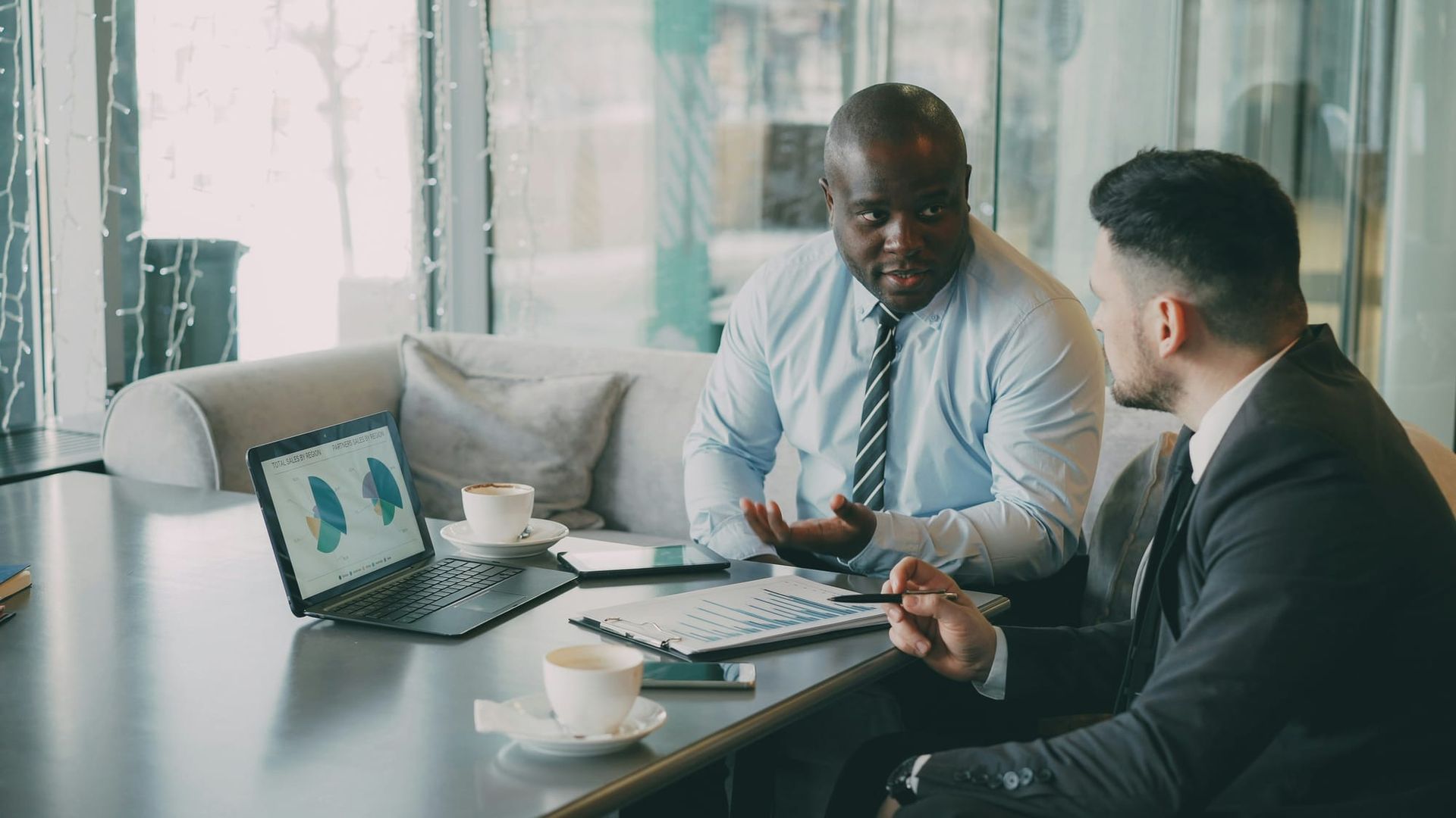 Two people discussing paperwork on a desk in a professional office setting - check a financial advisor
