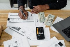 Person using a calculator beside financial documents and charts on a desk - 2025 Survey of Consumer Finances