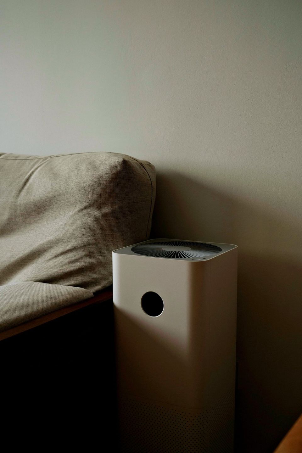 Compact air purifier in a black background showing vents and power button - choose an air purifier