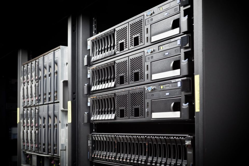 Rows of rack-mounted servers and storage equipment inside a dimly lit data center - Cohere funding